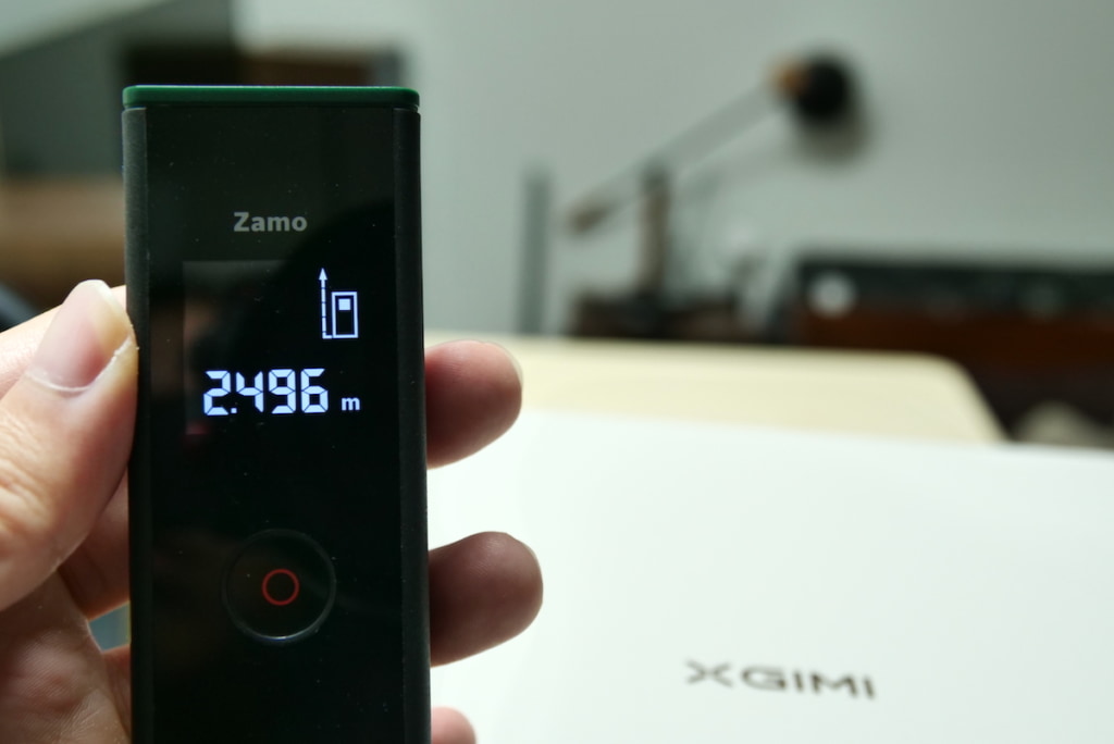 XGIMI HORIZON Ultraと壁の距離をレーザー距離計で測定している画像